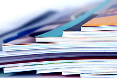 Close-up of a stack of magazines or books showing their spines and edges.